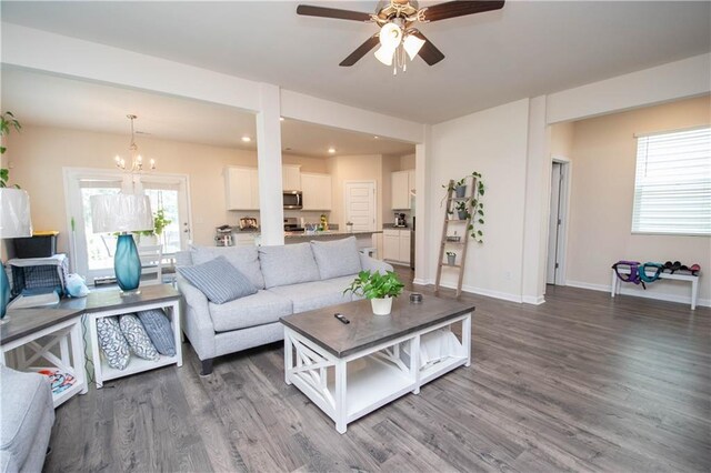 living room with ceiling fan with notable chandelier and wood-type flooring