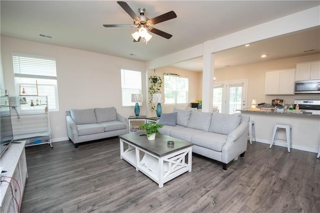 living area featuring a ceiling fan, baseboards, visible vents, and dark wood-style flooring