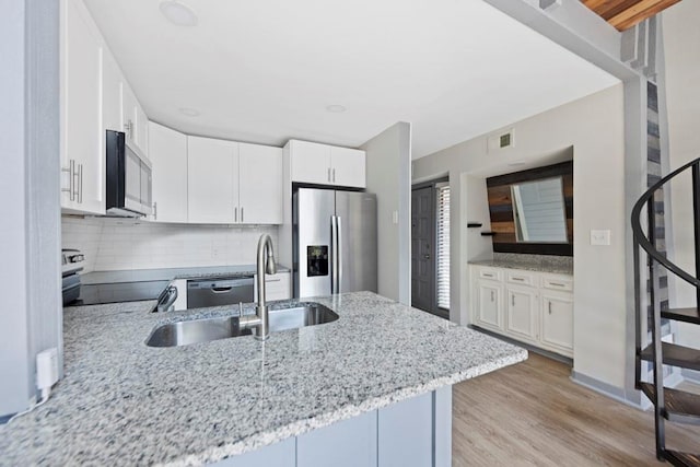 kitchen with decorative backsplash, appliances with stainless steel finishes, sink, light hardwood / wood-style floors, and white cabinetry