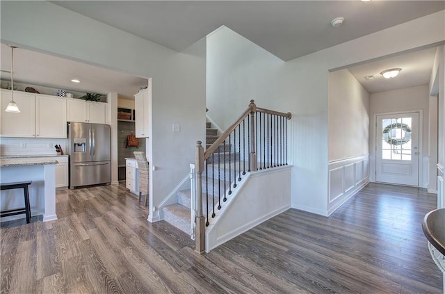 kitchen featuring white cabinetry, hanging light fixtures, stainless steel refrigerator with ice dispenser, light stone countertops, and dark wood-type flooring