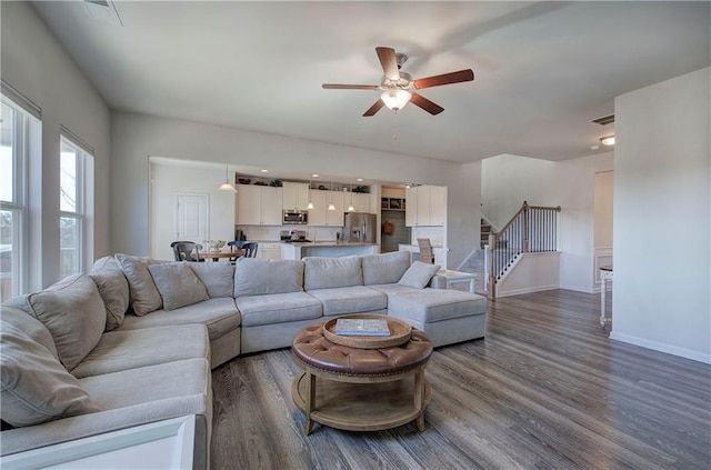 living area featuring visible vents, dark wood-type flooring, ceiling fan, baseboards, and stairway