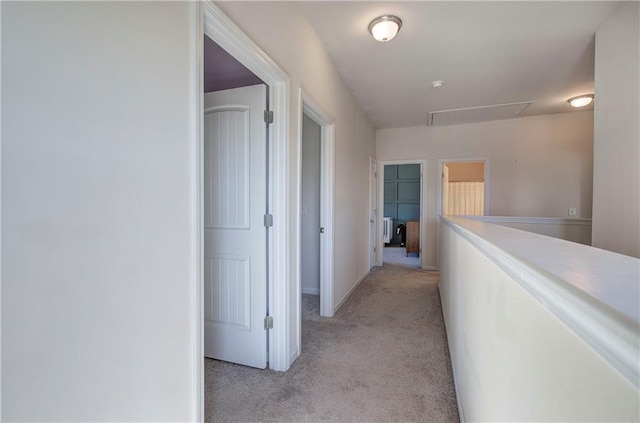 corridor with light carpet and attic access