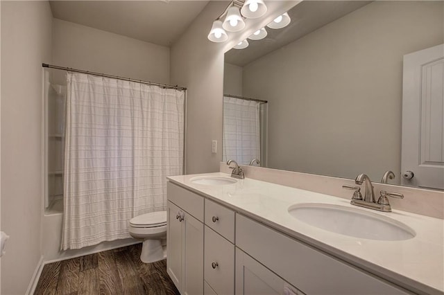 bathroom featuring double vanity, toilet, wood finished floors, and a sink