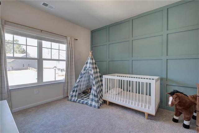 bedroom featuring a decorative wall, baseboards, carpet, and visible vents