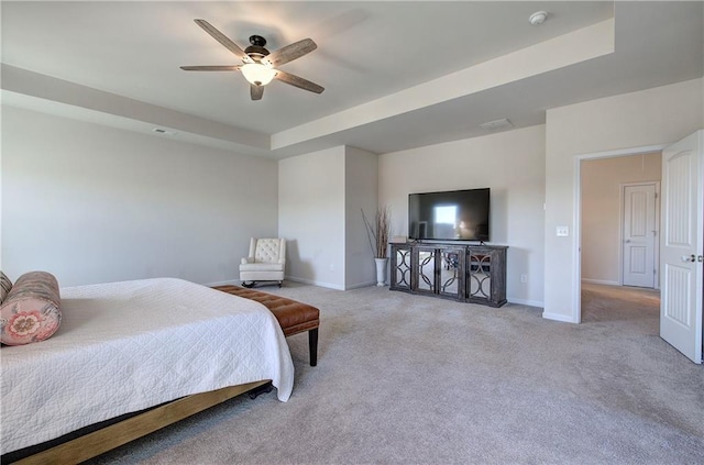 carpeted bedroom with a tray ceiling and ceiling fan