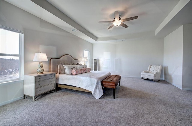 bedroom featuring light colored carpet, a raised ceiling, and ceiling fan