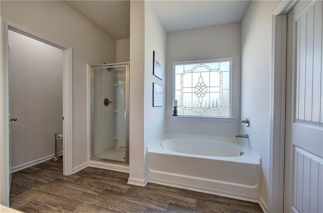 full bathroom with baseboards, wood finished floors, a garden tub, and a stall shower