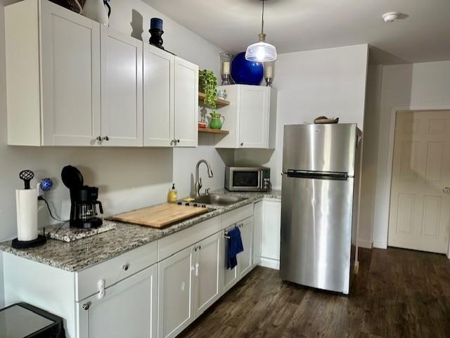 kitchen featuring dark wood-style floors, open shelves, a sink, white cabinets, and appliances with stainless steel finishes