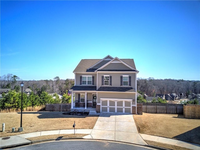 view of front of property featuring a front yard, fence, a porch, concrete driveway, and a garage