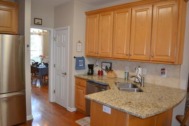 kitchen featuring sink, light stone counters, appliances with stainless steel finishes, light hardwood / wood-style floors, and backsplash