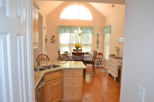 kitchen featuring lofted ceiling, sink, light stone countertops, stainless steel dishwasher, and light wood-type flooring