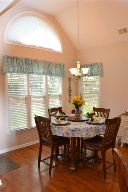 dining room featuring vaulted ceiling, hardwood / wood-style floors, and a notable chandelier