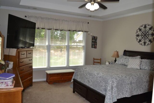 carpeted bedroom with a tray ceiling, ornamental molding, and ceiling fan