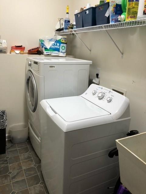 washroom with dark tile patterned flooring, sink, and washer and dryer