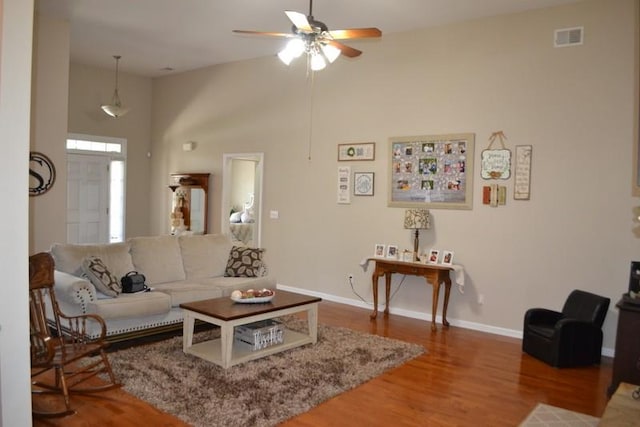 living room featuring a high ceiling, wood-type flooring, and ceiling fan