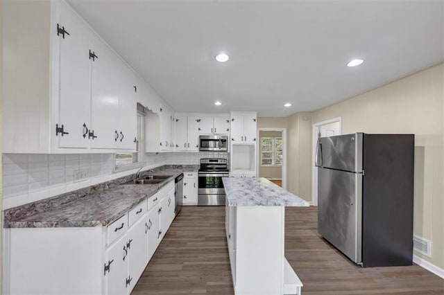 9258 Westview Dr SW, Covington, GA 30014 - kitchen with wood finished floors, a kitchen island, appliances with stainless steel finishes, a sink, and backsplash