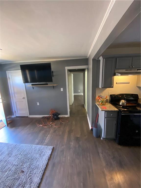 3734 Travis Blvd, Macon, GA 31206 - kitchen featuring black electric range oven, under cabinet range hood, dark wood-style floors, baseboards, and ornamental molding
