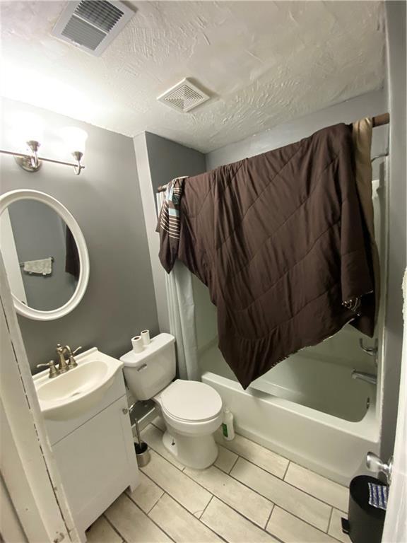 3734 Travis Blvd, Macon, GA 31206 - bathroom with vanity, shower / bath combination with curtain, toilet, tile patterned flooring, and a textured ceiling