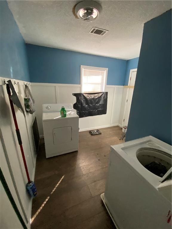3734 Travis Blvd, Macon, GA 31206 - laundry room featuring wainscoting, washing machine and dryer, a textured ceiling, and a decorative wall