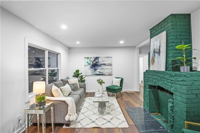 living room featuring a premium fireplace, recessed lighting, baseboards, and wood finished floors