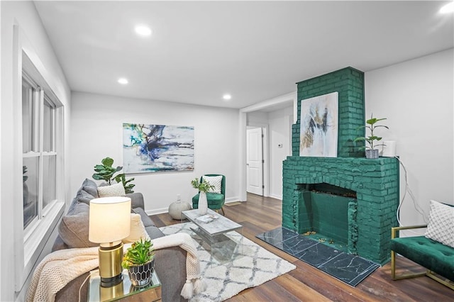 living area with dark wood finished floors, a brick fireplace, recessed lighting, and baseboards