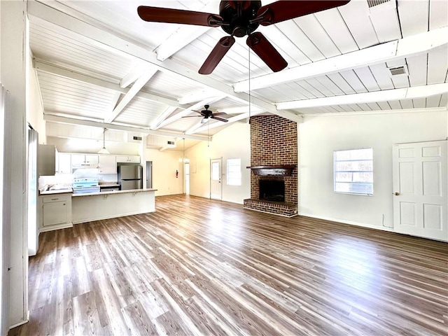 unfurnished living room featuring visible vents, a brick fireplace, ceiling fan, lofted ceiling with beams, and wood finished floors