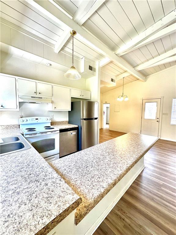 kitchen featuring lofted ceiling with beams, a sink, dark wood-style floors, stainless steel appliances, and white cabinets