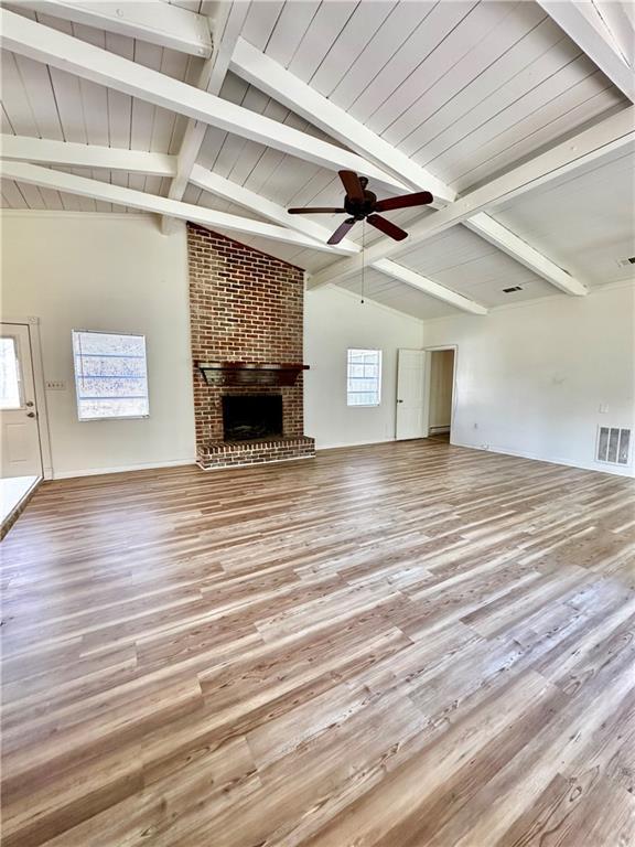 unfurnished living room featuring visible vents, lofted ceiling with beams, a ceiling fan, and wood finished floors