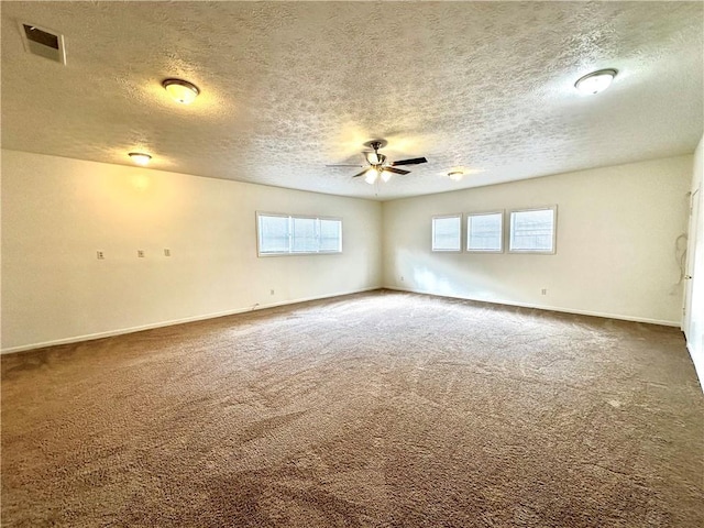 empty room featuring baseboards, visible vents, carpet floors, ceiling fan, and a textured ceiling