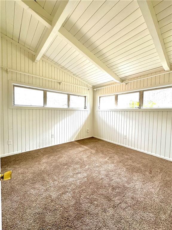 spare room featuring lofted ceiling with beams, carpet flooring, and a wealth of natural light