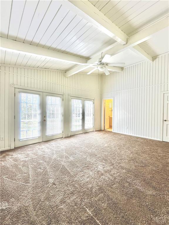 unfurnished room with french doors, carpet, beamed ceiling, and ceiling fan