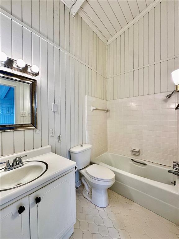 bathroom with vanity, shower / tub combination, toilet, and wood walls