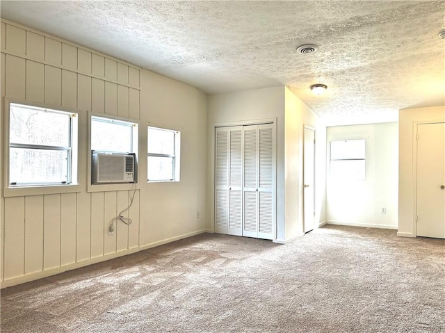 unfurnished bedroom featuring cooling unit, visible vents, carpet floors, and a textured ceiling