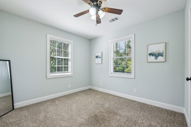 carpeted spare room with a ceiling fan, visible vents, and baseboards