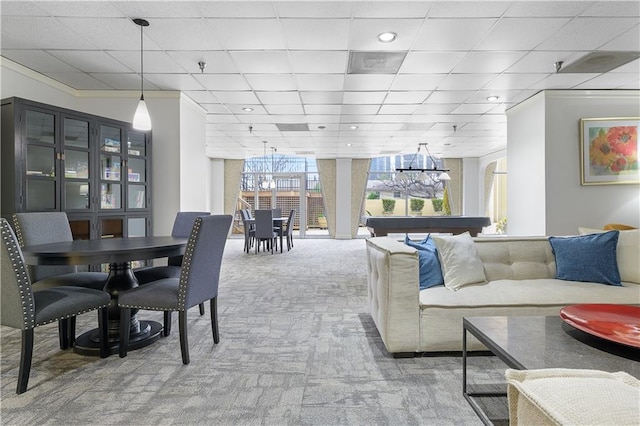 carpeted living room featuring a paneled ceiling and a chandelier