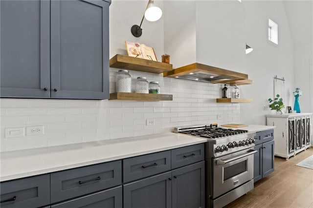 kitchen with open shelves, high end stainless steel range oven, gray cabinets, and custom range hood