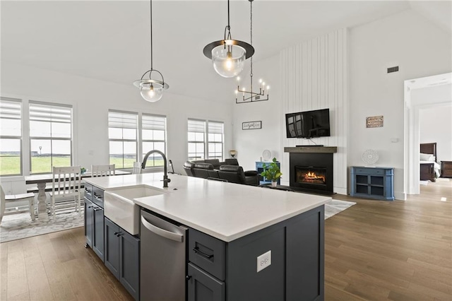 kitchen featuring dark wood-type flooring, gray cabinets, a sink, stainless steel dishwasher, and a large fireplace