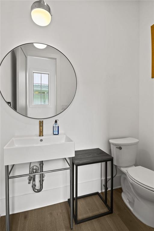 bathroom featuring toilet, wood finished floors, baseboards, and a sink