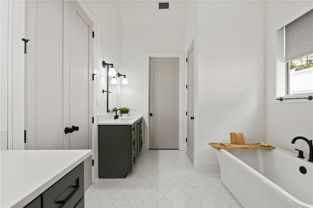 bathroom with visible vents, a freestanding bath, vanity, and tile patterned flooring