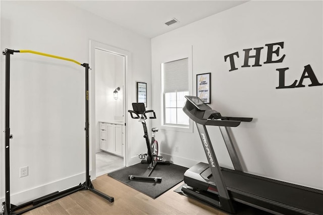 exercise area featuring visible vents, baseboards, and wood finished floors