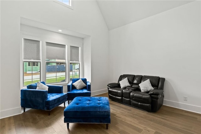 living room featuring baseboards, high vaulted ceiling, and wood finished floors