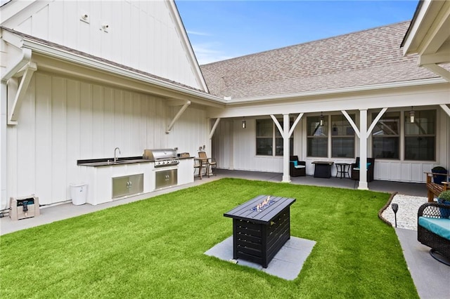 view of yard featuring an outdoor kitchen, a fire pit, a patio, and a sink