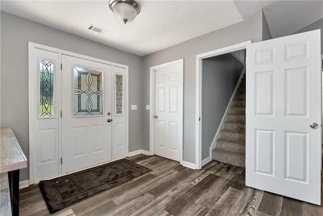 foyer featuring a textured ceiling, visible vents, wood finished floors, stairway, and baseboards
