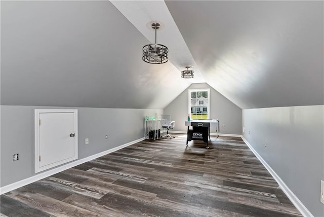 interior space with baseboards, wood finished floors, and vaulted ceiling