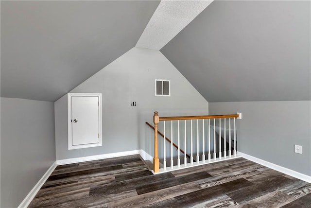 additional living space featuring baseboards, visible vents, wood finished floors, and lofted ceiling