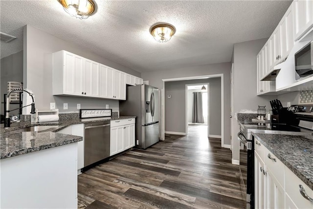 kitchen with a sink, stainless steel appliances, dark wood-style flooring, and a textured ceiling