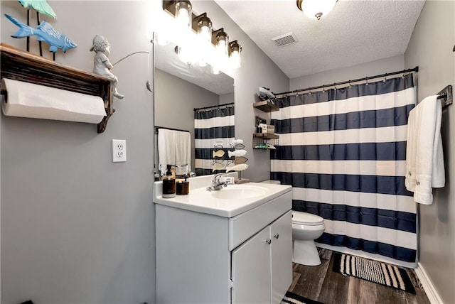 bathroom featuring visible vents, vanity, wood finished floors, toilet, and a textured ceiling
