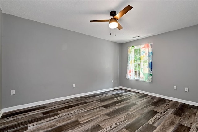 spare room featuring a ceiling fan, baseboards, visible vents, and dark wood-type flooring