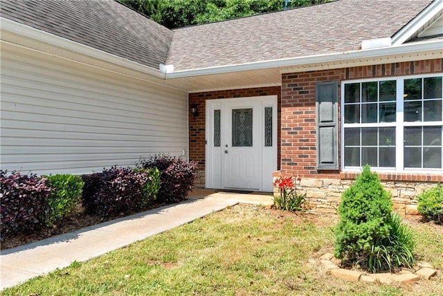entrance to property with roof with shingles and brick siding