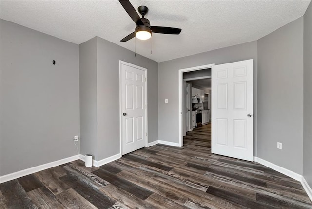 unfurnished bedroom with baseboards, ceiling fan, a textured ceiling, and dark wood-type flooring